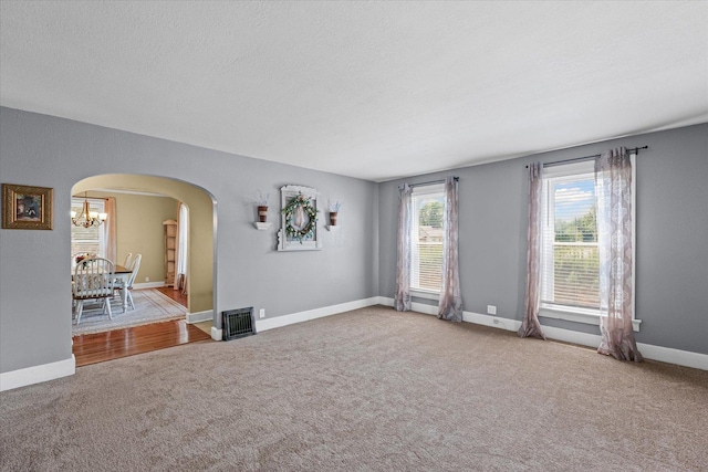 835 E Pells St, Paxton, IL 60957 - empty room with arched walkways, carpet flooring, a chandelier, and a textured ceiling