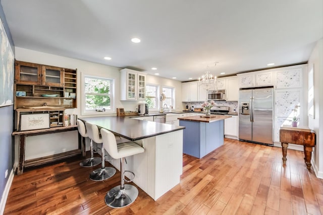 653 Blackstone Pl, Highland Park, IL 60035 - kitchen with appliances with stainless steel finishes, light wood-style floors, white cabinets, a peninsula, and recessed lighting