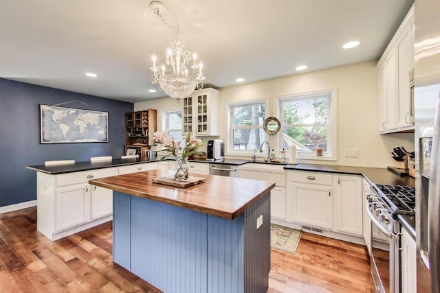 653 Blackstone Pl, Highland Park, IL 60035 - kitchen featuring appliances with stainless steel finishes, wooden counters, a peninsula, white cabinetry, and recessed lighting