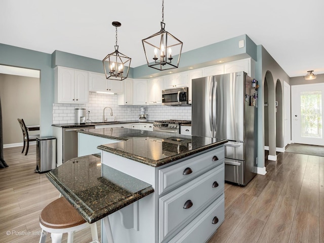 624 63rd St, Downers Grove, IL 60516 - kitchen with stainless steel appliances, a kitchen island, arched walkways, decorative backsplash, and a chandelier