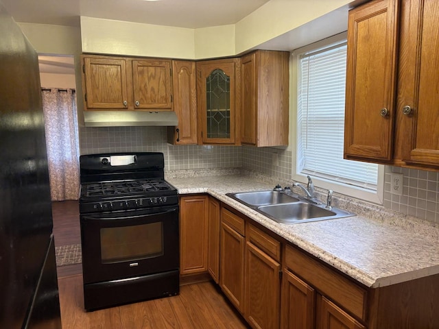 2841 10th St, Rockford, IL 61108 - kitchen with black gas range, under cabinet range hood, brown cabinetry, and light countertops