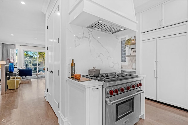 1469 W Byron St Unit 2, Chicago, IL 60613 - kitchen featuring premium appliances, premium range hood, light wood-style floors, white cabinets, and tasteful backsplash