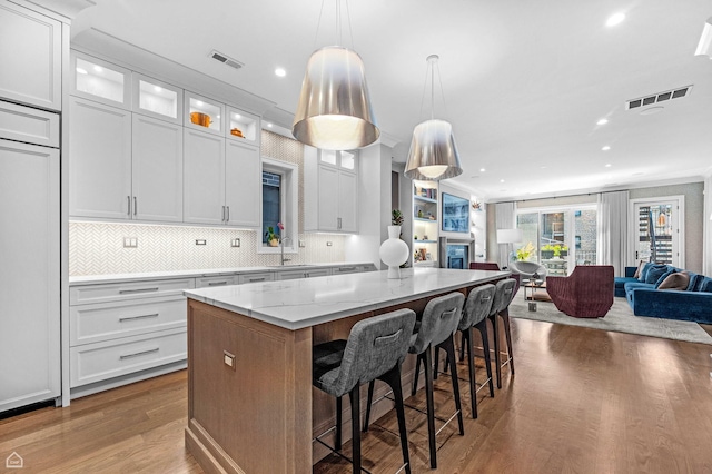 1469 W Byron St Unit 2, Chicago, IL 60613 - kitchen with open floor plan, a center island, wood finished floors, light stone counters, and white cabinets