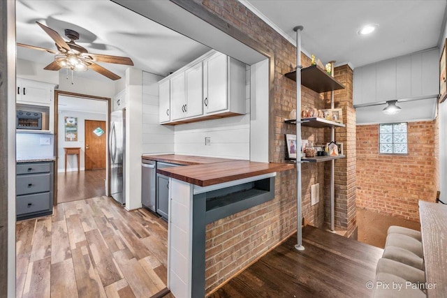8920 Mcvicker Ave, Morton Grove, IL 60053 - kitchen with butcher block counters, stainless steel appliances, brick wall, and light wood-type flooring