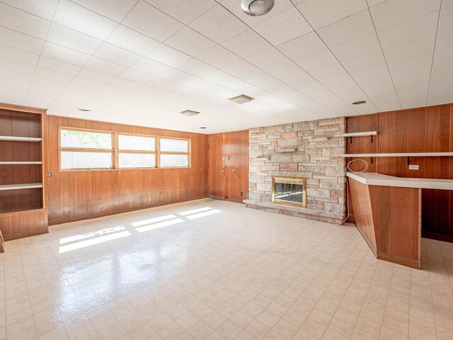 6052 W 128th St, Palos Heights, IL 60463 - unfurnished living room featuring wooden walls, a stone fireplace, built in shelves, and tile patterned floors