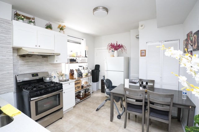 2834 S Union Ave, Chicago, IL 60616 - kitchen with stainless steel range with gas cooktop, under cabinet range hood, freestanding refrigerator, white cabinets, and tasteful backsplash