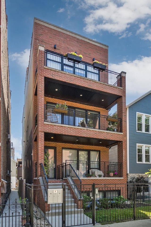 1011 N Winchester Ave Unit 2, Chicago, IL 60622 - view of front of house with a balcony, a fenced front yard, brick siding, a gate, and stairway