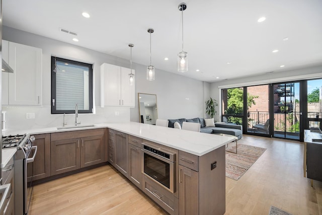 1011 N Winchester Ave Unit 2, Chicago, IL 60622 - kitchen with stainless steel gas range, open floor plan, light wood-type flooring, a peninsula, and recessed lighting