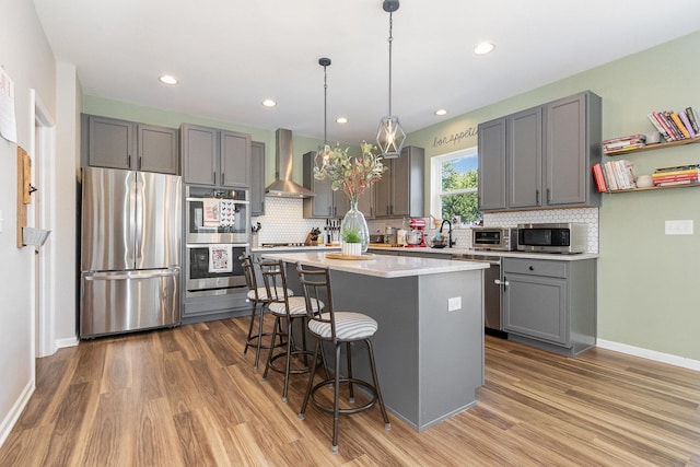 26550 W Old Stage Ln, Channahon, IL 60410 - kitchen featuring appliances with stainless steel finishes, wall chimney exhaust hood, gray cabinets, wood finished floors, and recessed lighting