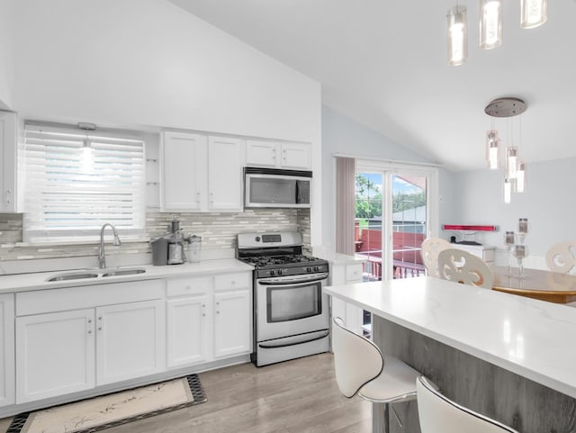 18 E 155th Pl, South Holland, IL 60473 - kitchen featuring appliances with stainless steel finishes, lofted ceiling, white cabinetry, light wood finished floors, and decorative backsplash