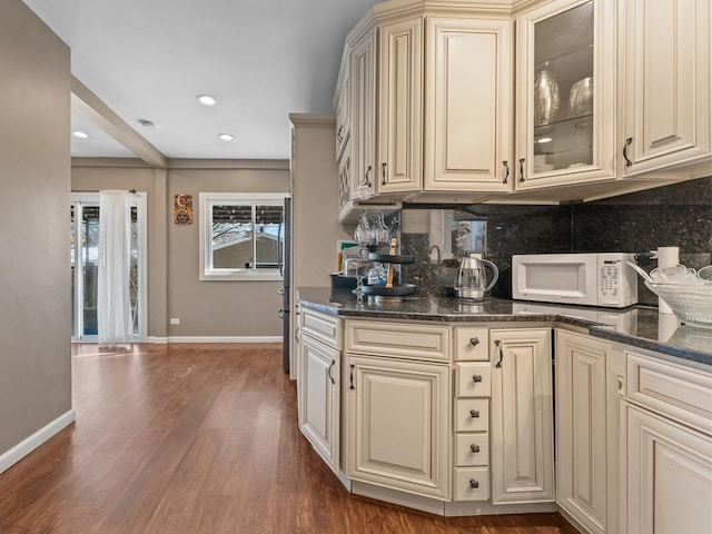 2529 Scoville Ave, Berwyn, IL 60402 - kitchen featuring cream cabinetry, white microwave, tasteful backsplash, dark wood-style floors, and glass insert cabinets
