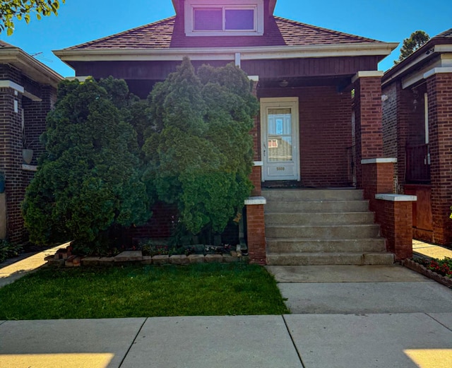 5608 S Spaulding Ave, Chicago, IL 60629 - view of exterior entry with a shingled roof, brick siding, and covered porch