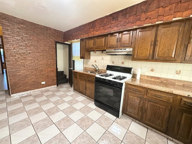 5608 S Spaulding Ave, Chicago, IL 60629 - kitchen with gas range, under cabinet range hood, brick wall, backsplash, and light stone countertops