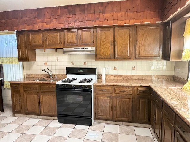 5608 S Spaulding Ave, Chicago, IL 60629 - kitchen featuring gas range, under cabinet range hood, tasteful backsplash, light stone countertops, and light tile patterned floors