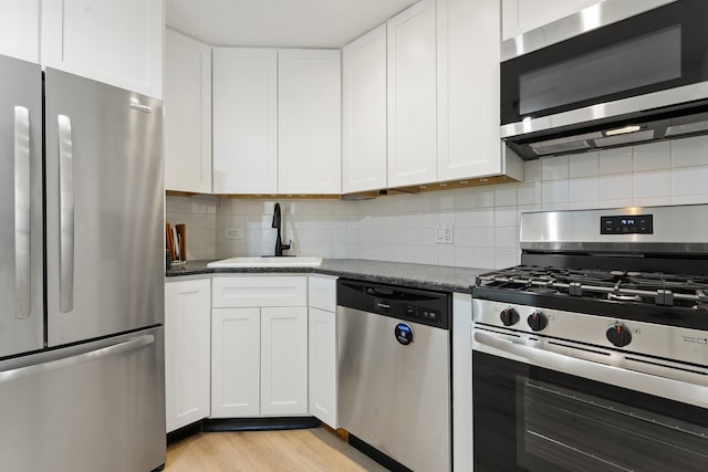 3200 N Lake Shore Dr Unit 302, Chicago, IL 60657 - kitchen featuring stainless steel appliances, white cabinets, decorative backsplash, light wood-style floors, and dark stone counters
