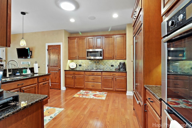 9516 Thousand Oaks Dr, Spring Grove, IL 60081 - kitchen with appliances with stainless steel finishes, light wood-type flooring, brown cabinets, tasteful backsplash, and pendant lighting