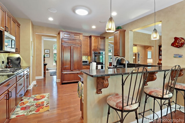 9516 Thousand Oaks Dr, Spring Grove, IL 60081 - kitchen with stainless steel appliances, a breakfast bar area, light wood-style flooring, pendant lighting, and recessed lighting