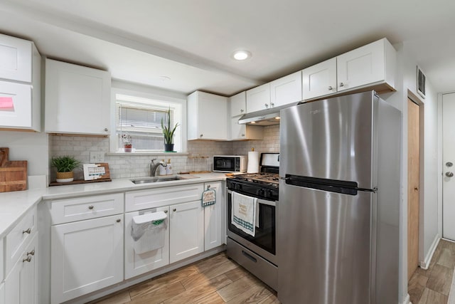 1630 N Avers Ave, Chicago, IL 60647 - kitchen featuring stainless steel appliances, light wood-style flooring, white cabinets, tasteful backsplash, and light countertops