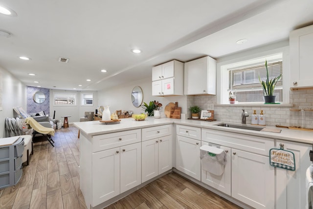 1630 N Avers Ave, Chicago, IL 60647 - kitchen featuring a peninsula, white cabinetry, decorative backsplash, light countertops, and light wood-style flooring