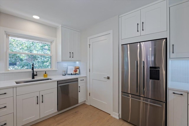 7418 Kildare Ave, Skokie, IL 60076 - kitchen featuring stainless steel appliances, light wood-style flooring, decorative backsplash, white cabinetry, and light countertops