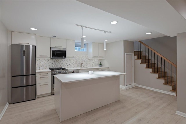 7418 Kildare Ave, Skokie, IL 60076 - kitchen featuring stainless steel appliances, white cabinets, light wood finished floors, a kitchen island, and tasteful backsplash