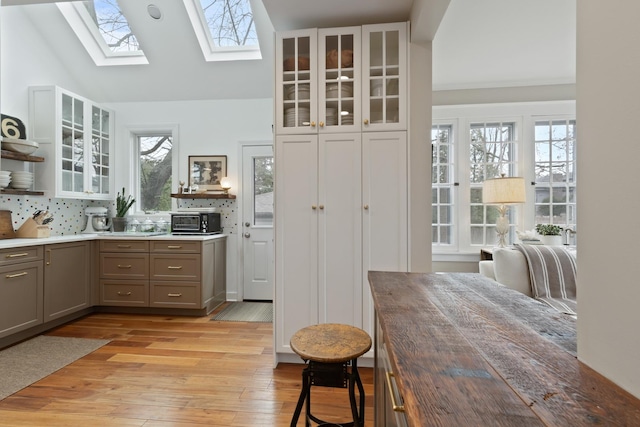 1123 Linden Ave, Wilmette, IL 60091 - kitchen with gray cabinetry, a skylight, glass insert cabinets, light wood-style floors, and light countertops