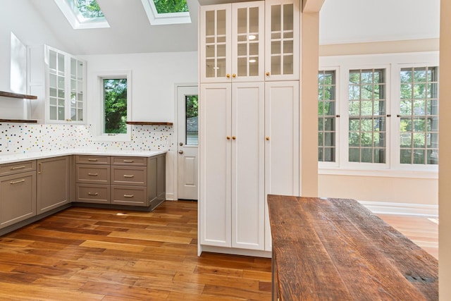 1123 Linden Ave, Wilmette, IL 60091 - kitchen featuring gray cabinets, a skylight, light wood-style flooring, glass insert cabinets, and decorative backsplash