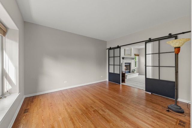 24006 Skyler Ln, Plainfield, IL 60586 - unfurnished room with plenty of natural light, light wood-style floors, and a barn door