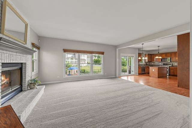 24006 Skyler Ln, Plainfield, IL 60586 - unfurnished living room with light colored carpet, a fireplace, and a chandelier