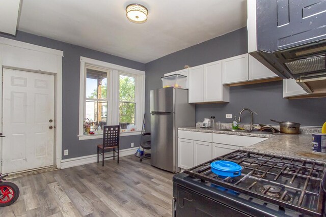 3810 W Ohio St, Chicago, IL 60624 - kitchen featuring freestanding refrigerator, black range with gas cooktop, white cabinets, light wood-style floors, and light stone counters