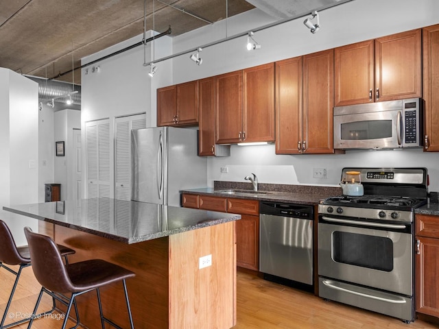 833 W 15th Pl Unit 502, Chicago, IL 60608 - kitchen with appliances with stainless steel finishes, track lighting, light wood-type flooring, a kitchen island, and a kitchen bar