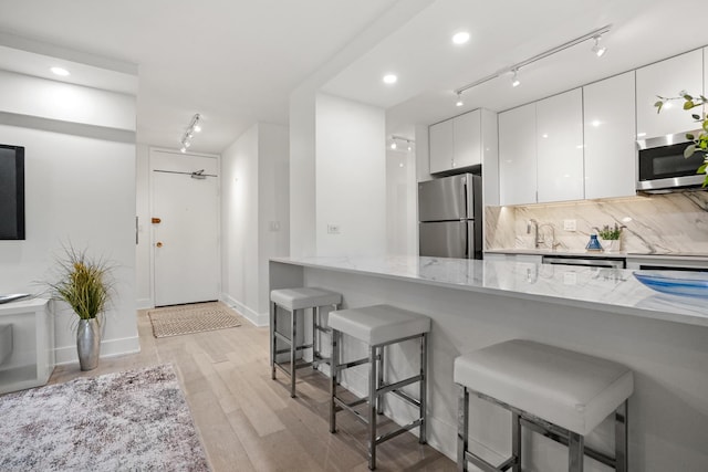 88 W Schiller St Unit 904, Chicago, IL 60610 - kitchen featuring appliances with stainless steel finishes, a breakfast bar area, light stone countertops, white cabinets, and modern cabinets