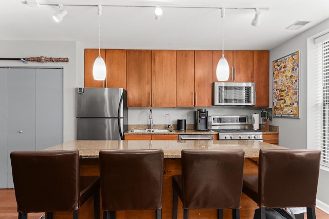 1600 N Halsted St Unit 3C, Chicago, IL 60614 - kitchen with appliances with stainless steel finishes, rail lighting, brown cabinets, and hanging light fixtures