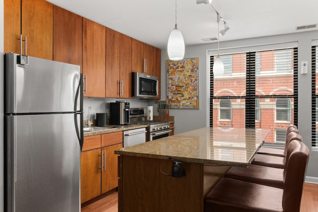 1600 N Halsted St Unit 3C, Chicago, IL 60614 - kitchen with stainless steel appliances, light wood finished floors, brown cabinets, and a breakfast bar area