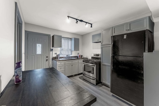 1621 N Central Park Ave, Chicago, IL 60647 - kitchen with stainless steel gas range, freestanding refrigerator, light wood-style floors, rail lighting, and dark countertops