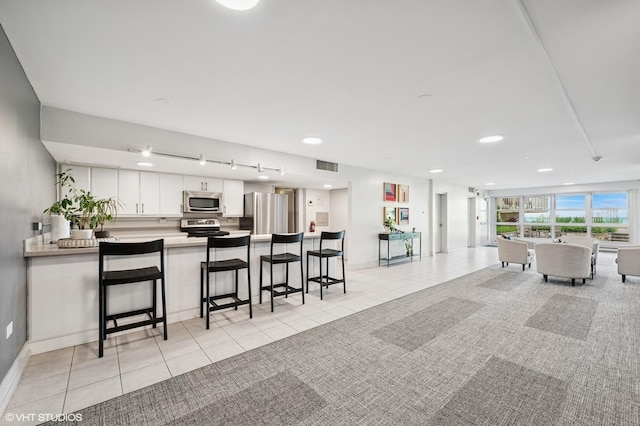 1440 Sheridan Rd Unit 101, Wilmette, IL 60091 - kitchen featuring stainless steel appliances, light tile patterned flooring, open floor plan, a kitchen breakfast bar, and white cabinets