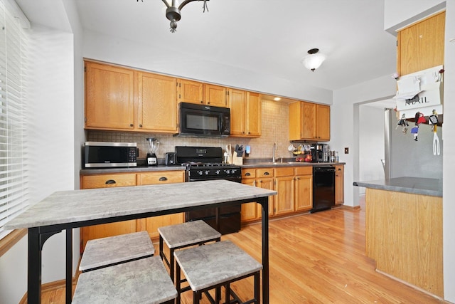 1484 Joshel Ct, Geneva, IL 60134 - kitchen with black appliances, tasteful backsplash, light wood-style flooring, and a kitchen bar