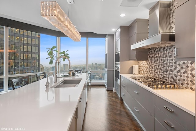 401 N Wabash Ave Unit 44F, Chicago, IL 60611 - kitchen with wall chimney exhaust hood, gray cabinets, stainless steel appliances, dark wood-style floors, and tasteful backsplash