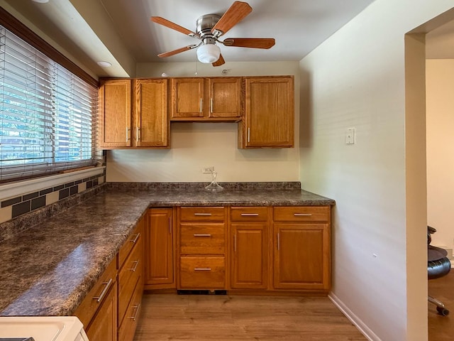 1840 W Hatherleigh Ct Unit 1E, Mount Prospect, IL 60056 - kitchen featuring brown cabinets, a ceiling fan, dark countertops, and light wood-type flooring