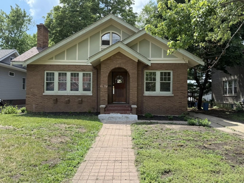 1911 S 4th St, Rockford, IL 61104 - view of front of house featuring brick siding, a front yard, and a chimney