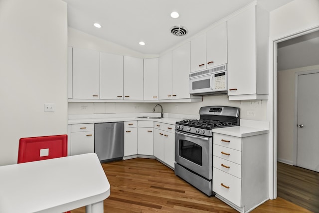 806 Lawler Ave, Wilmette, IL 60091 - kitchen featuring appliances with stainless steel finishes, light countertops, wood finished floors, white cabinetry, and recessed lighting