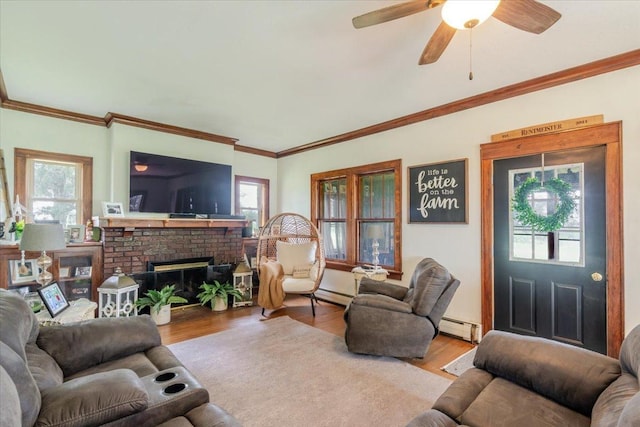 879 2300th Ave, Chestnut, IL 62518 - living room featuring wood finished floors, baseboard heating, ceiling fan, a brick fireplace, and crown molding