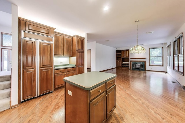 705 Wood Creek Dr, Antioch, IL 60002 - kitchen with a center island, a glass covered fireplace, light wood-style flooring, paneled fridge, and brown cabinets