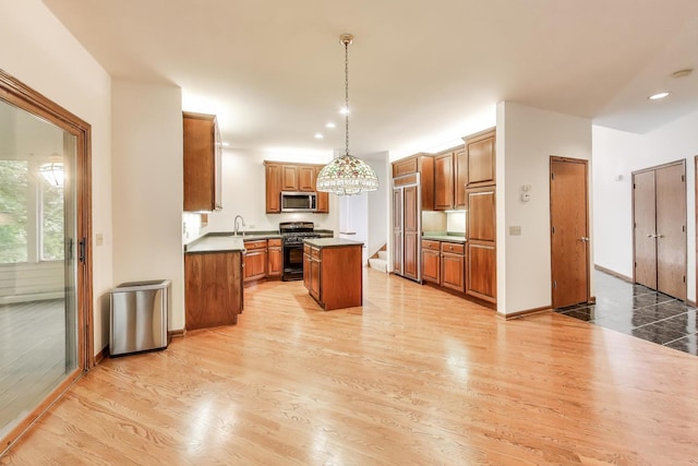 705 Wood Creek Dr, Antioch, IL 60002 - kitchen featuring stainless steel microwave, gas range oven, a kitchen island, brown cabinetry, and light wood-style floors