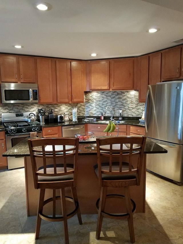4629 S Langley Ave, Chicago, IL 60653 - kitchen featuring appliances with stainless steel finishes, brown cabinetry, backsplash, a breakfast bar area, and recessed lighting