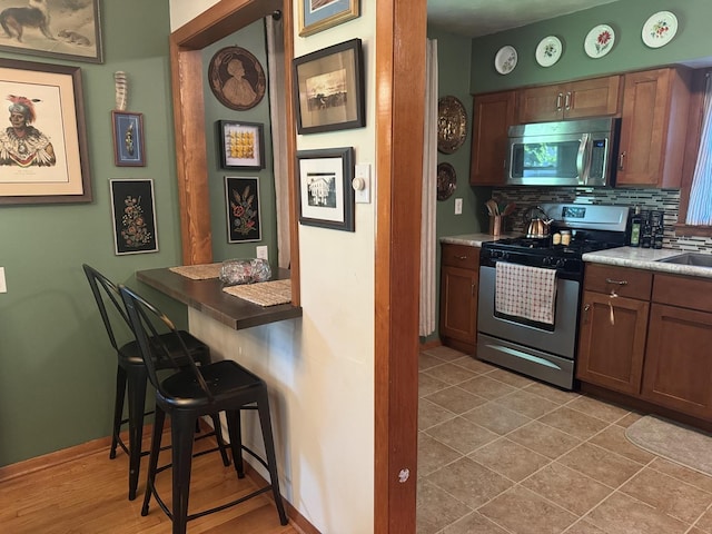 1202 E Van Buren St, Clinton, IL 61727 - kitchen with stainless steel appliances, decorative backsplash, a breakfast bar area, and light countertops