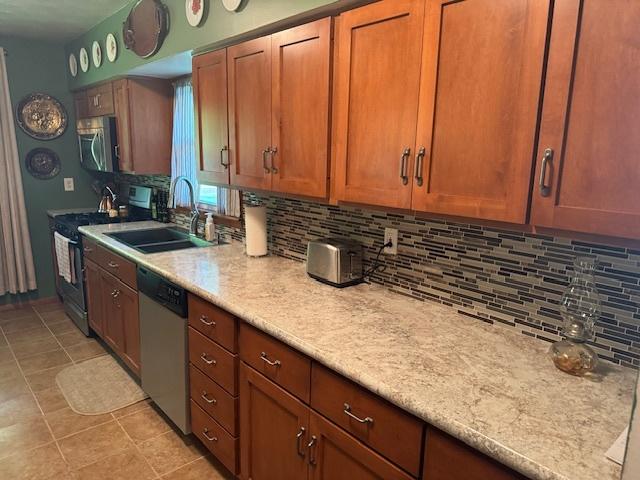 1202 E Van Buren St, Clinton, IL 61727 - kitchen featuring appliances with stainless steel finishes, tasteful backsplash, light countertops, and brown cabinetry