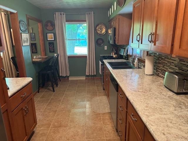 1202 E Van Buren St, Clinton, IL 61727 - kitchen with appliances with stainless steel finishes, decorative backsplash, and brown cabinetry