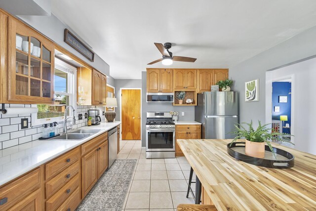 1110 N Main St, Normal, IL 61761 - kitchen with stainless steel appliances, tasteful backsplash, glass insert cabinets, light tile patterned flooring, and a ceiling fan