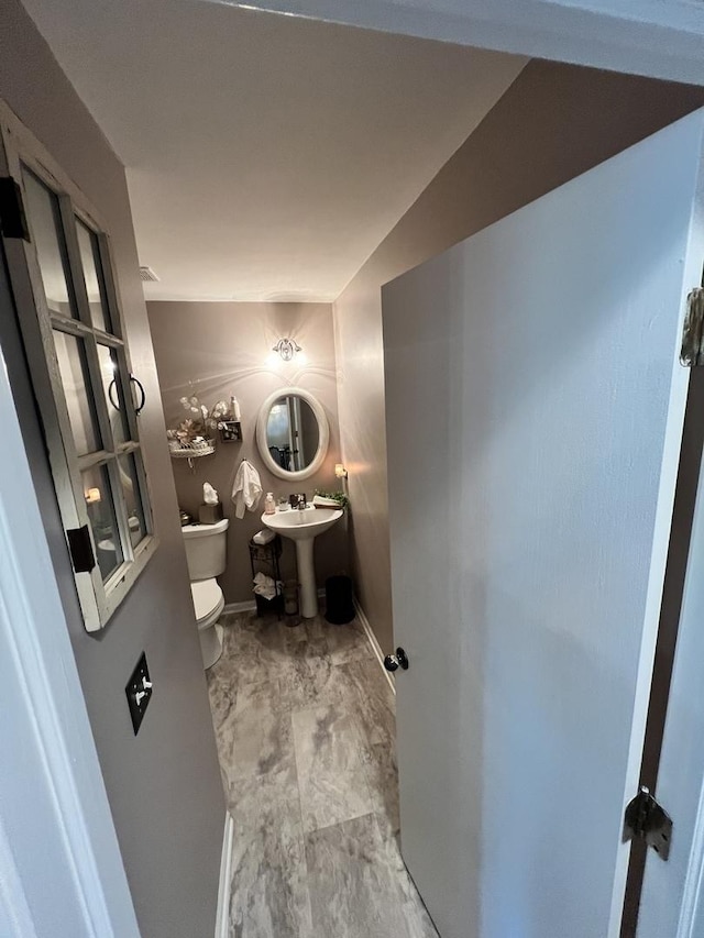 half bath featuring toilet and marble look tiles